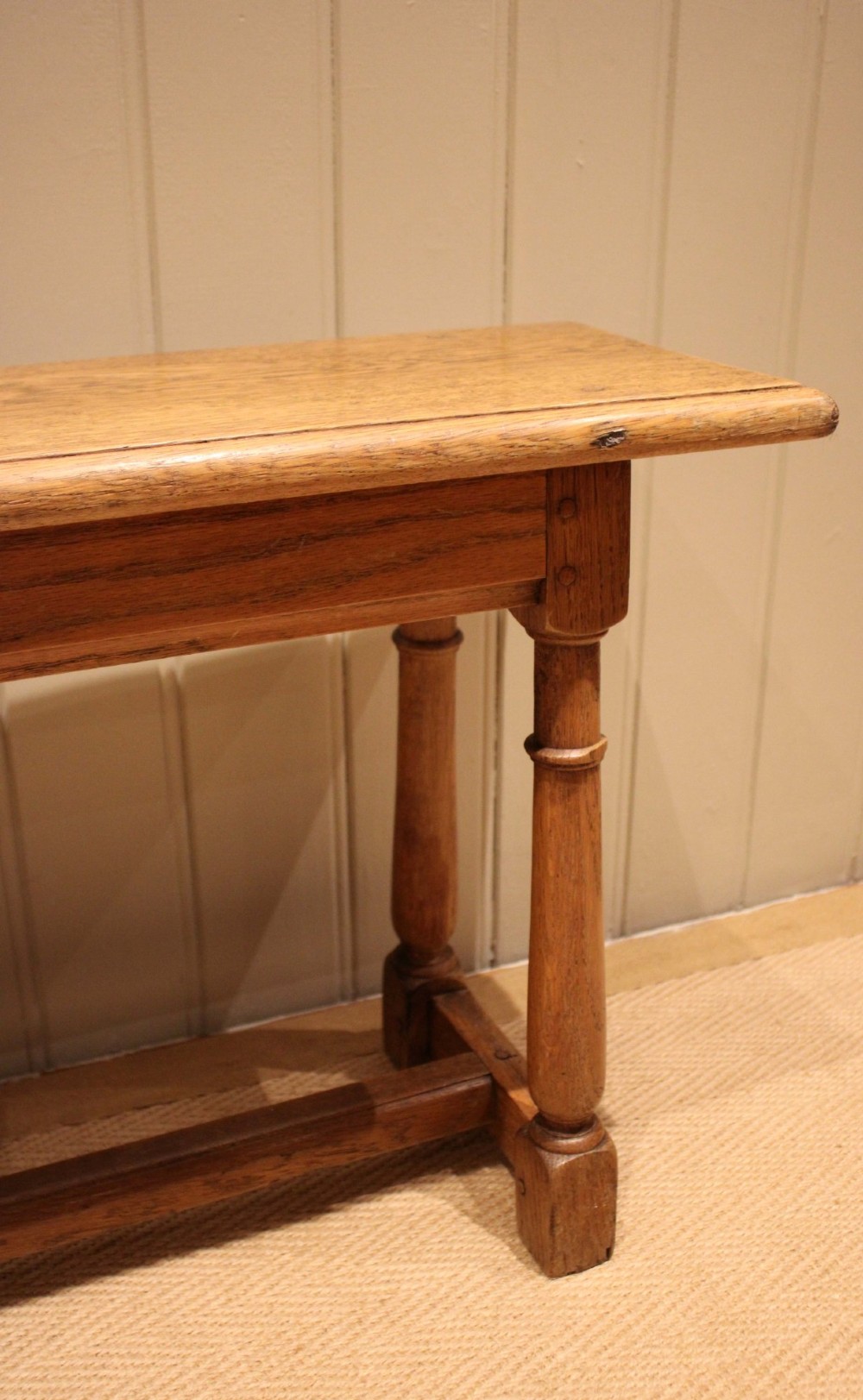 A long rectangular solid oak bench featuring turned legs connected by a low stretcher rail. View XII