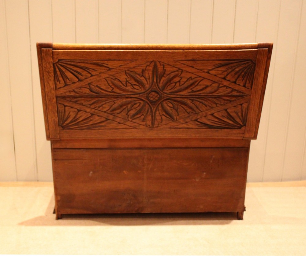 A solid golden oak coffer with detailed foliate and starburst hand-carvings across the hinged lid and front twin panels. View X