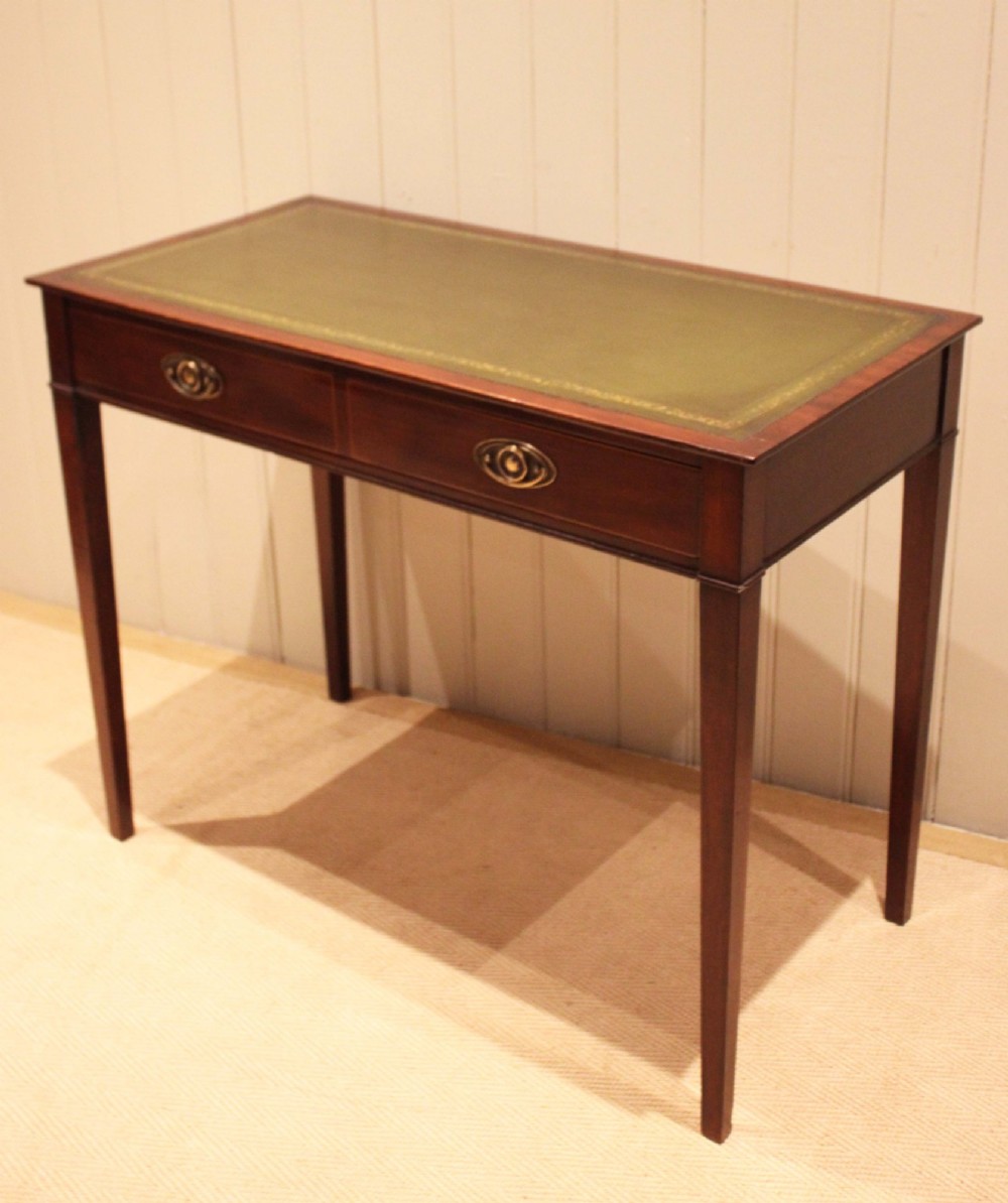 An early 19th-century mahogany writing desk featuring a green leather inset top, two frieze drawers with brass oval handles, and square tapered legs. View IV