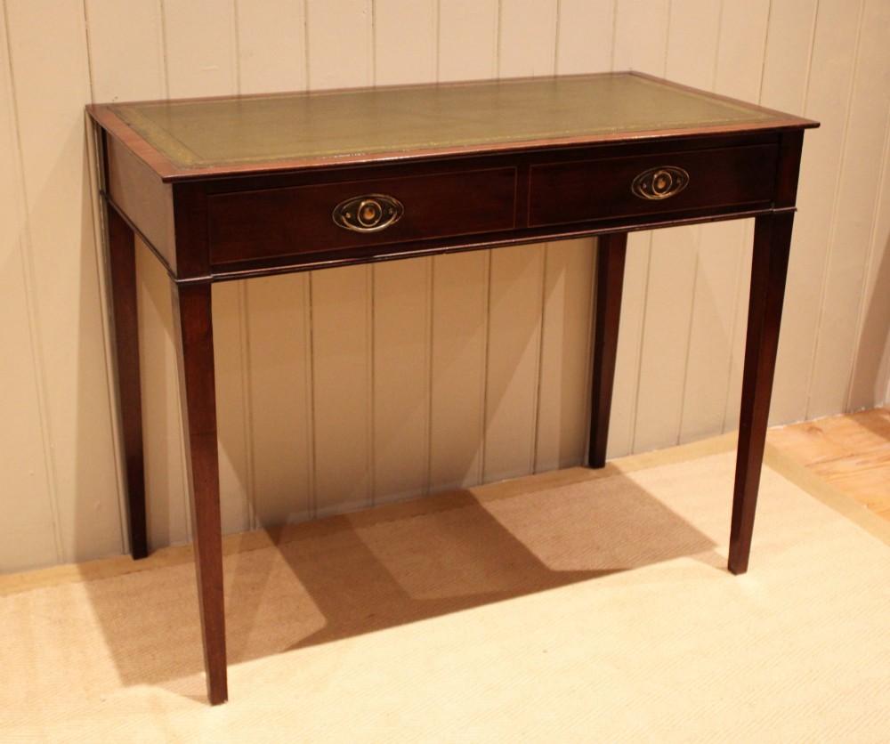 An early 19th-century mahogany writing desk featuring a green leather inset top, two frieze drawers with brass oval handles, and square tapered legs. View V