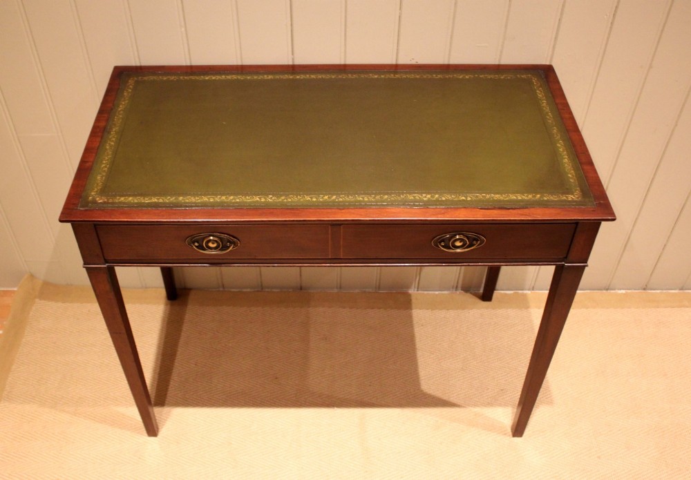 An early 19th-century mahogany writing desk featuring a green leather inset top, two frieze drawers with brass oval handles, and square tapered legs. View VII