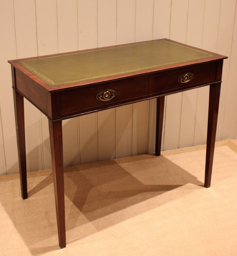 An early 19th-century mahogany writing desk featuring a green leather inset top, two frieze drawers with brass oval handles, and square tapered legs. View IX