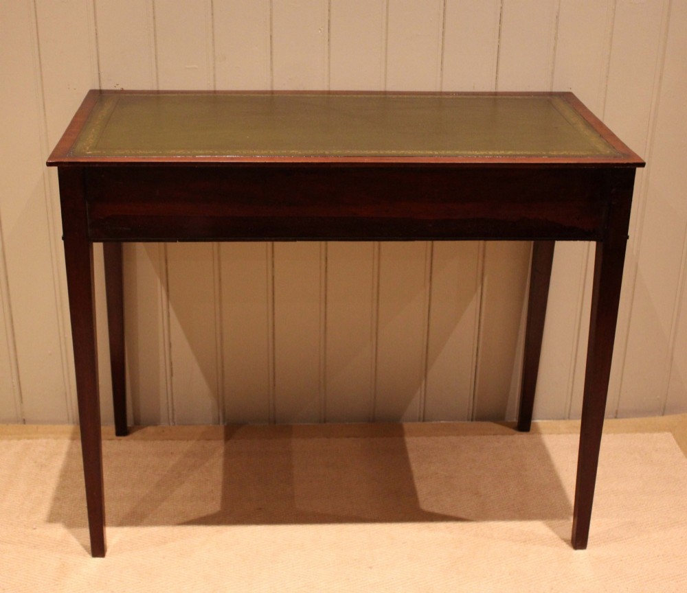 An early 19th-century mahogany writing desk featuring a green leather inset top, two frieze drawers with brass oval handles, and square tapered legs. View X