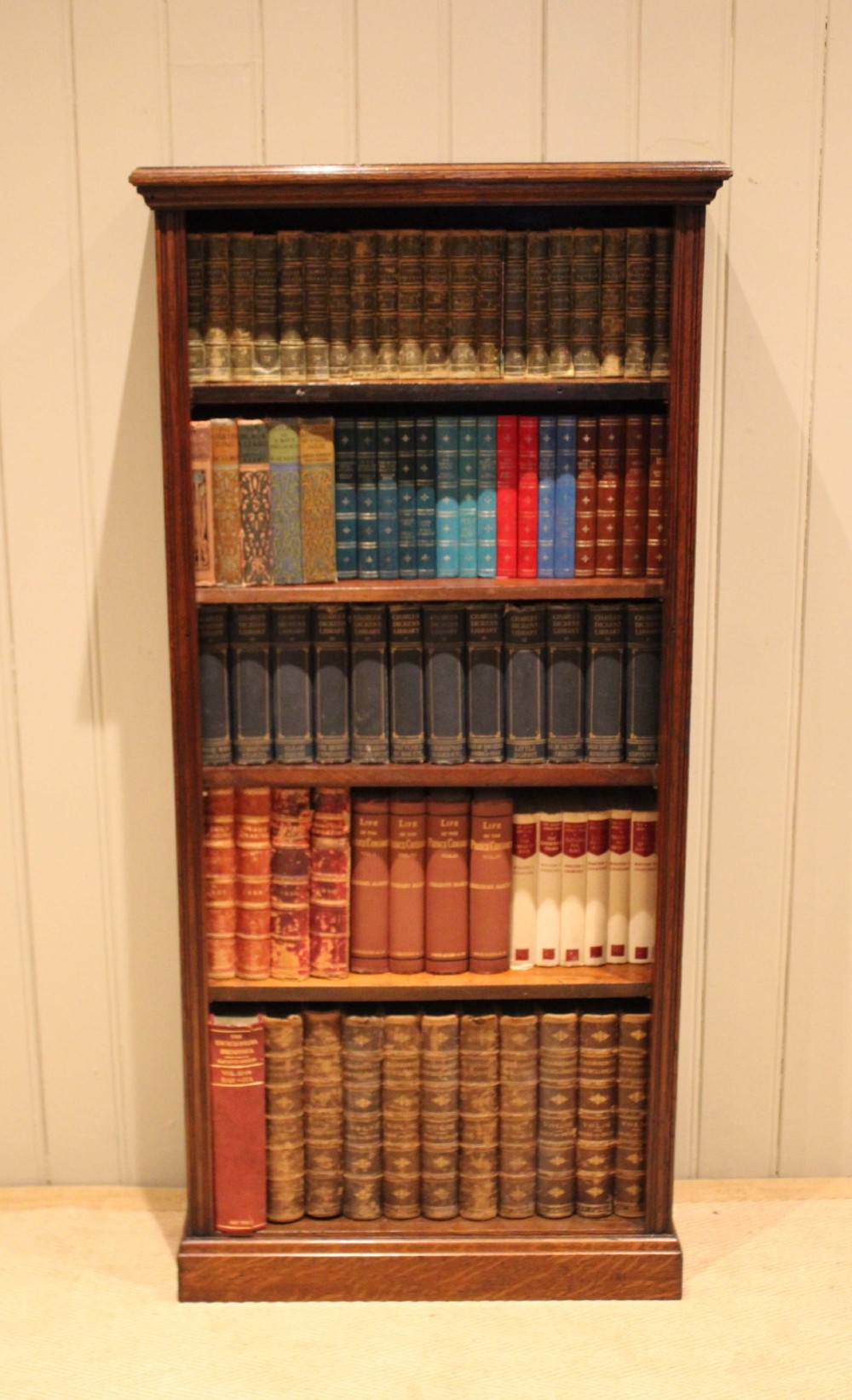 A tall late Victorian open oak bookcase featuring five adjustable shelves filled with books, a moulded top cornice, and a solid plinth base. View III