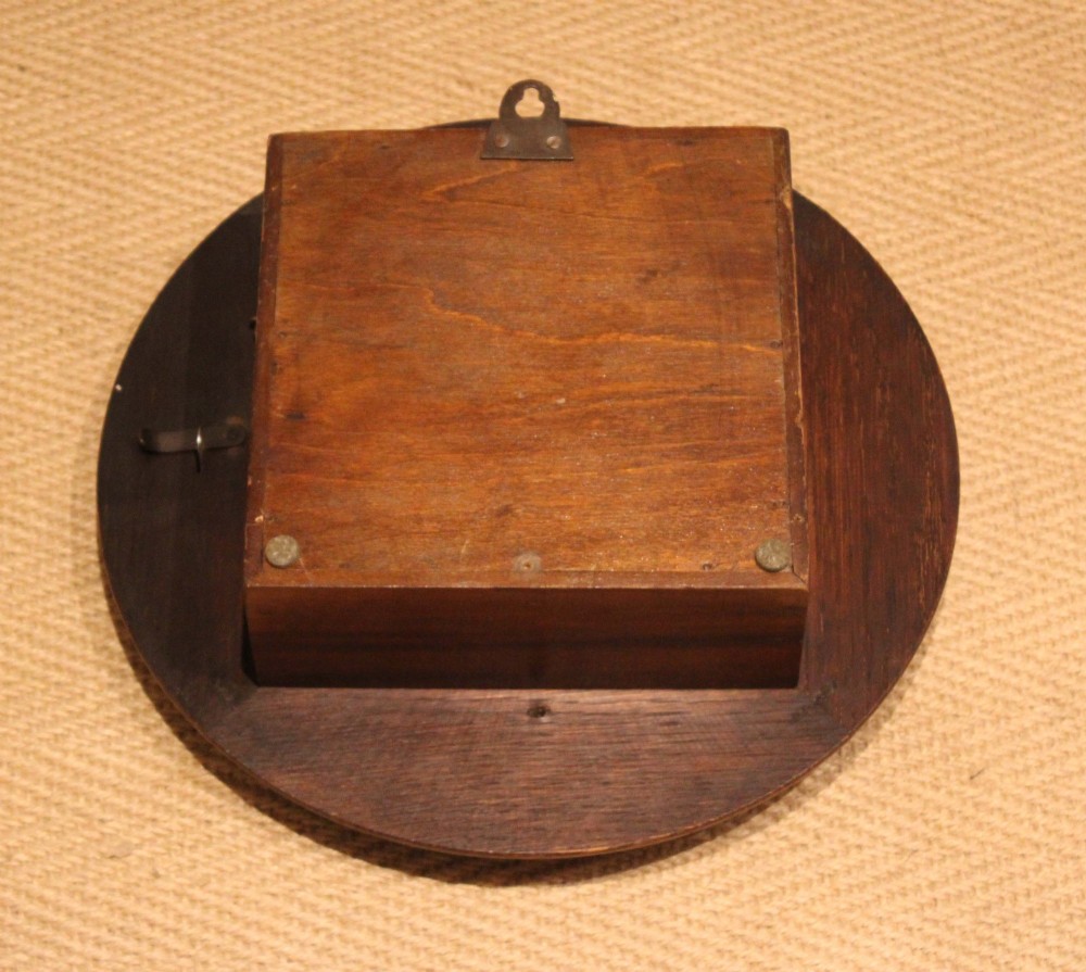 A circular early 20th-century wall clock featuring a moulded dark oak frame, a brass bezel, and a white dial face with black Roman numerals. View XI