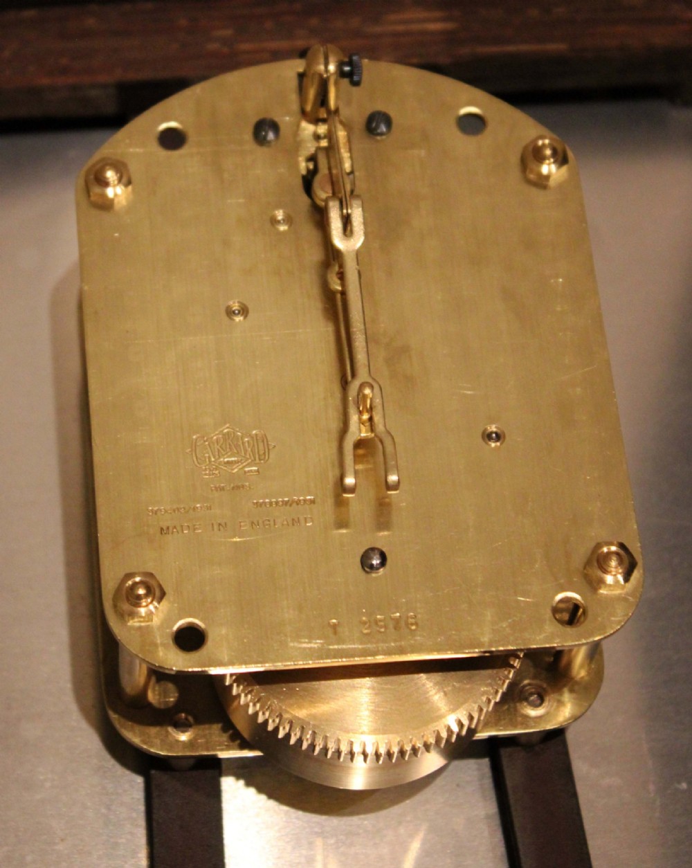 A circular early 20th-century wall clock featuring a moulded dark oak frame, a brass bezel, and a white dial face with black Roman numerals. View XII