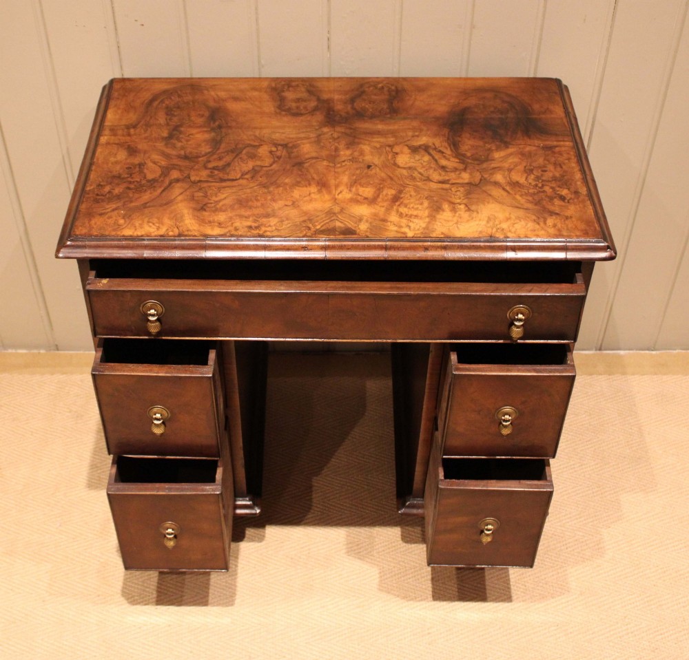 A small proportioned burr walnut pedestal desk featuring five drawers with brass drop handles and bracket feet. View IV