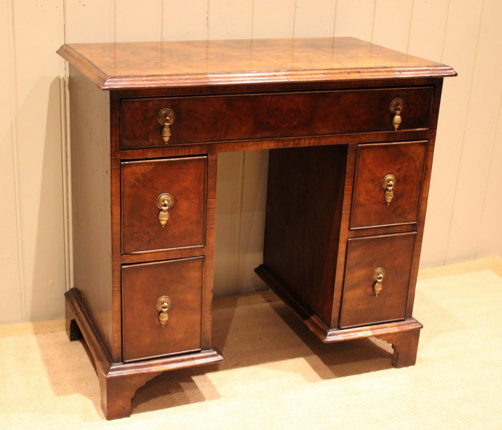 A small proportioned burr walnut pedestal desk featuring five drawers with brass drop handles and bracket feet. View IX