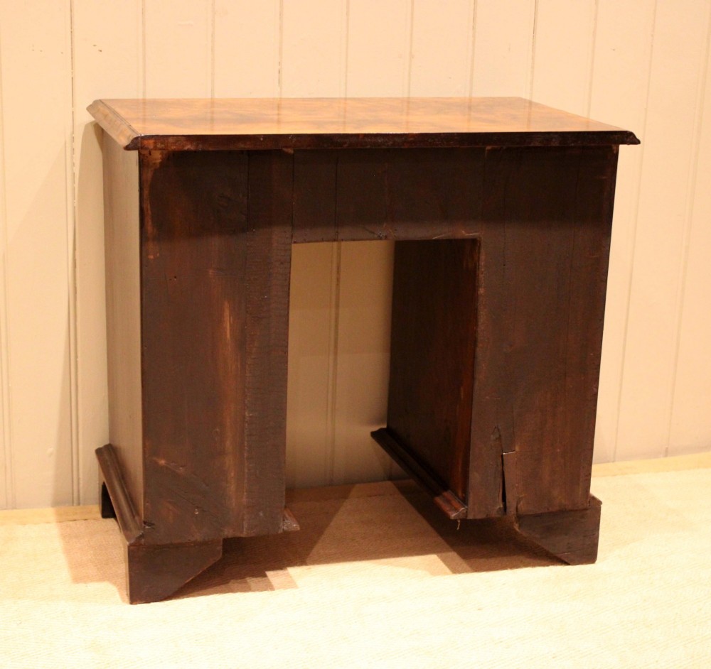 A small proportioned burr walnut pedestal desk featuring five drawers with brass drop handles and bracket feet. View X