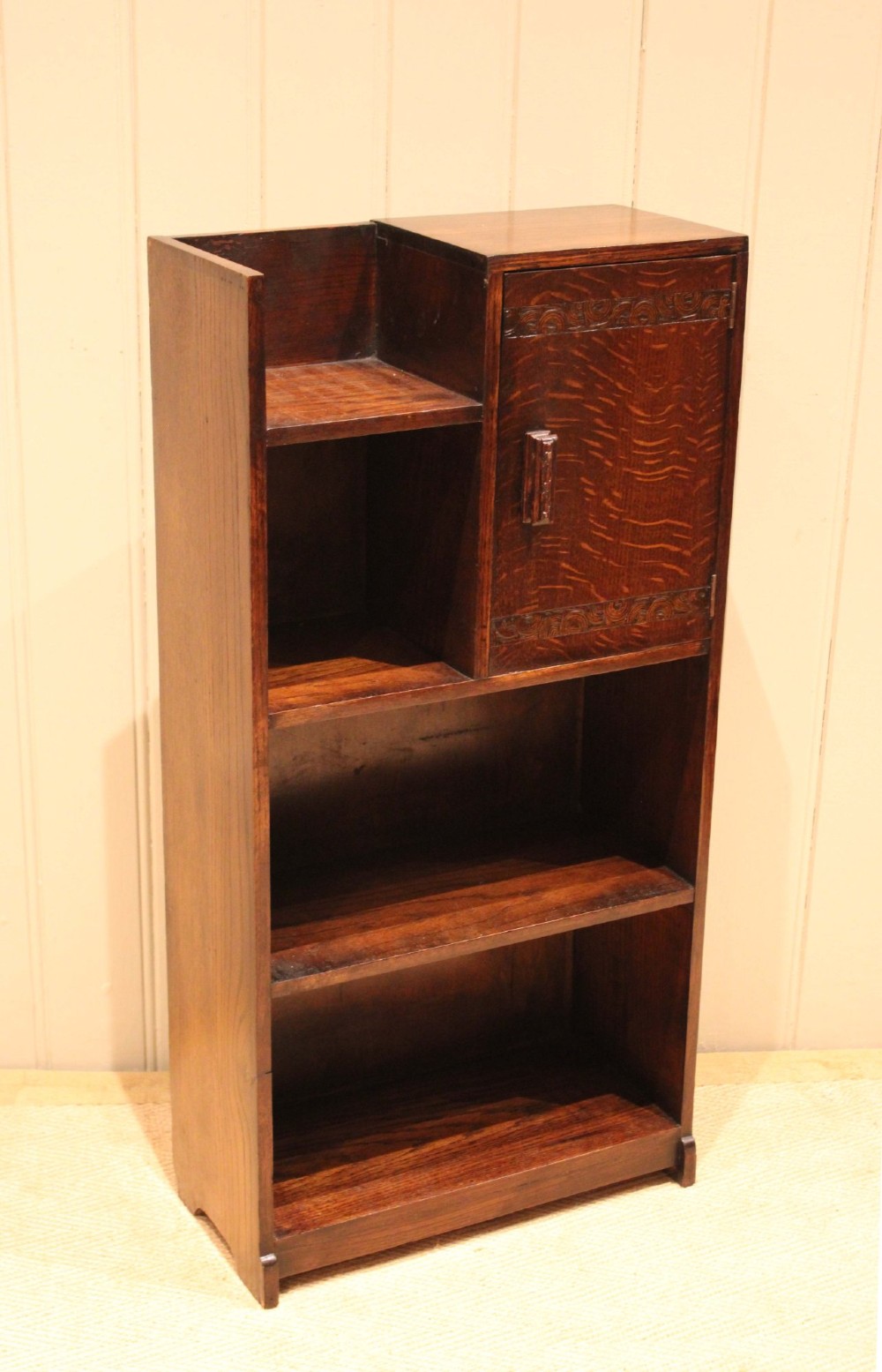 A dark oak Art Deco bookcase with open shelves on the left side, a small carved single door cabinet on the right, and two lower full-width shelves. View II
