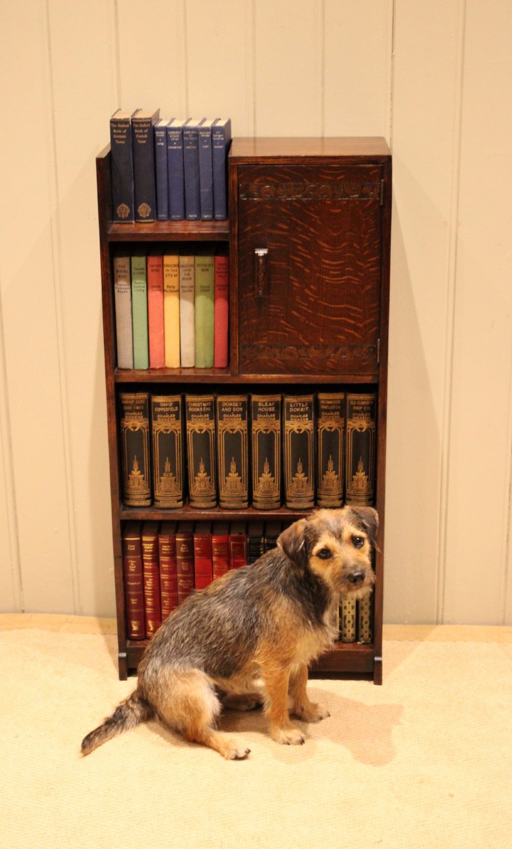 A dark oak Art Deco bookcase with open shelves on the left side, a small carved single door cabinet on the right, and two lower full-width shelves. View IX