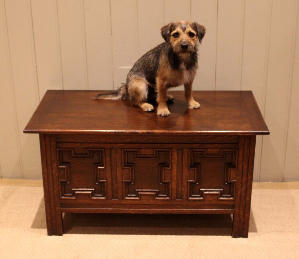 A dark oak coffer featuring three carved geometric recessed panels across the front and a flat hinged top lid. View III