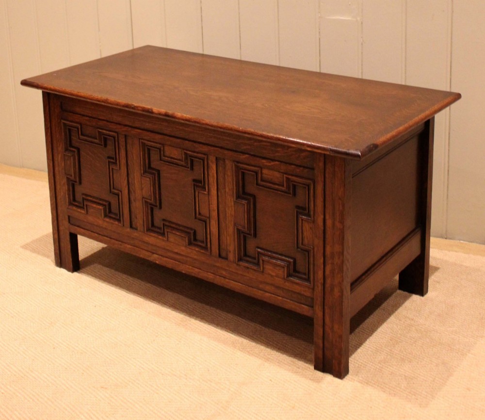 A dark oak coffer featuring three carved geometric recessed panels across the front and a flat hinged top lid. View VI