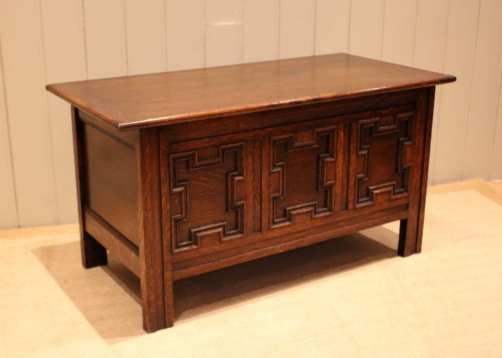 A dark oak coffer featuring three carved geometric recessed panels across the front and a flat hinged top lid. View VII