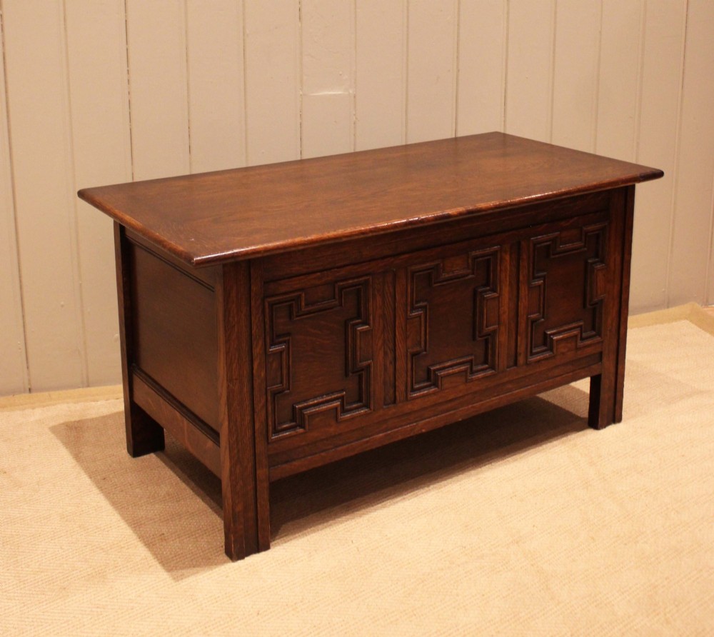 A dark oak coffer featuring three carved geometric recessed panels across the front and a flat hinged top lid. View VIII