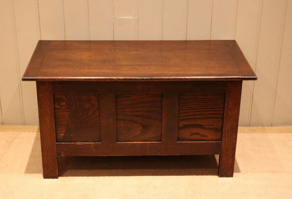 A dark oak coffer featuring three carved geometric recessed panels across the front and a flat hinged top lid. View IX