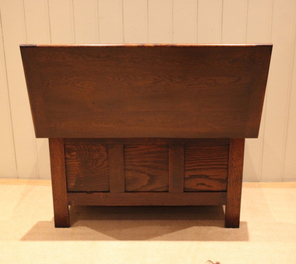 A dark oak coffer featuring three carved geometric recessed panels across the front and a flat hinged top lid. View X