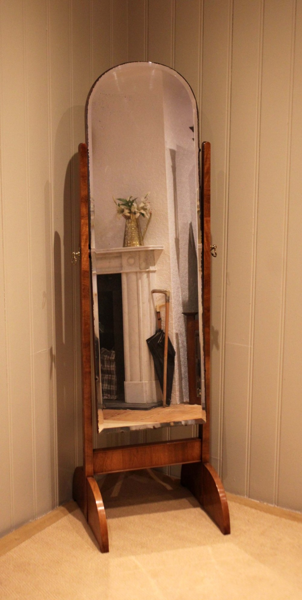 An Art Deco freestanding walnut cheval mirror featuring an arched glass plate set within a timber stand.