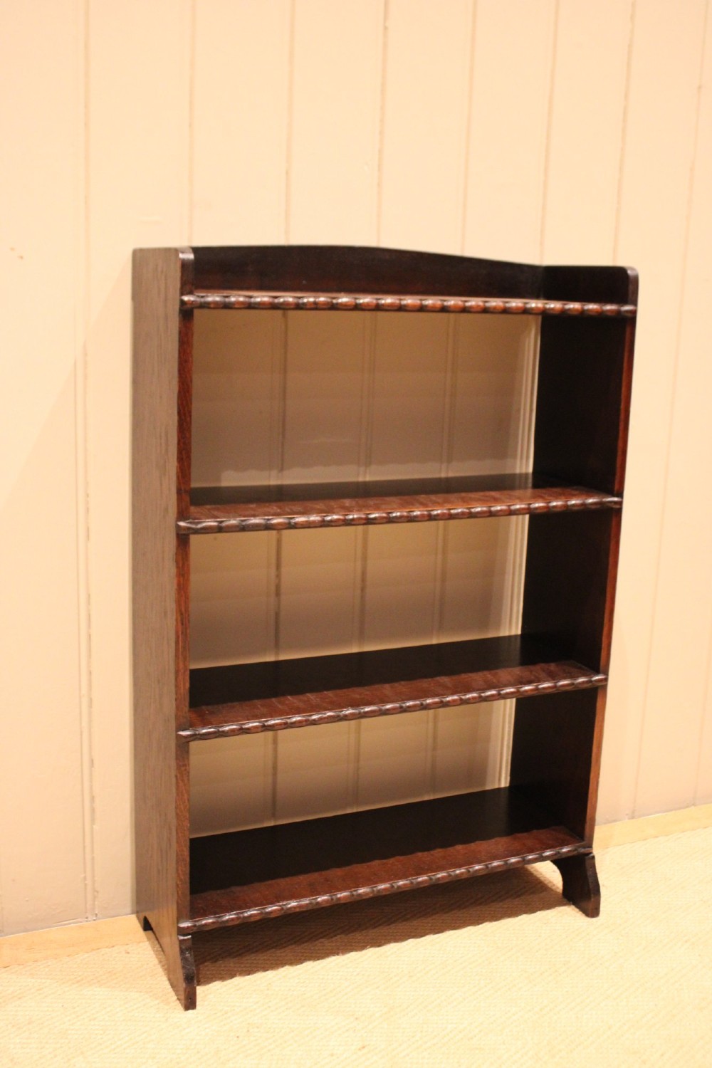 A small dark oak open bookcase with three fixed shelves and beaded edge moulding along each front shelf border. View II