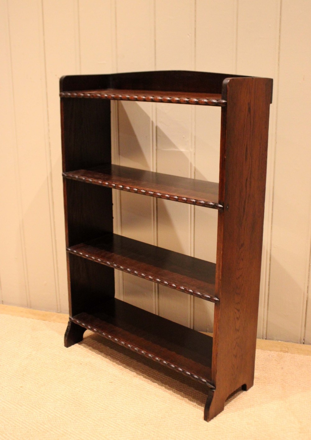 A small dark oak open bookcase with three fixed shelves and beaded edge moulding along each front shelf border. View X