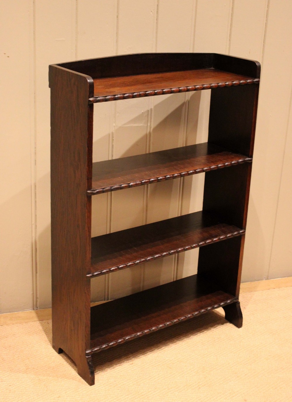 A small dark oak open bookcase with three fixed shelves and beaded edge moulding along each front shelf border. View XII