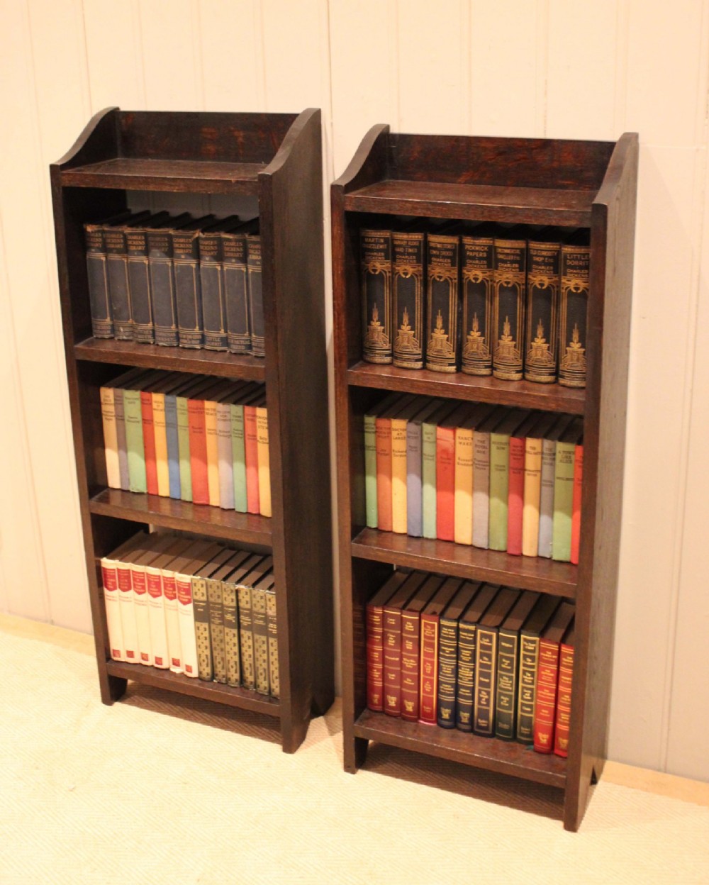 A small dark oak open bookcase featuring three open shelves filled with books and shaped side gallery panels at the top. View VII