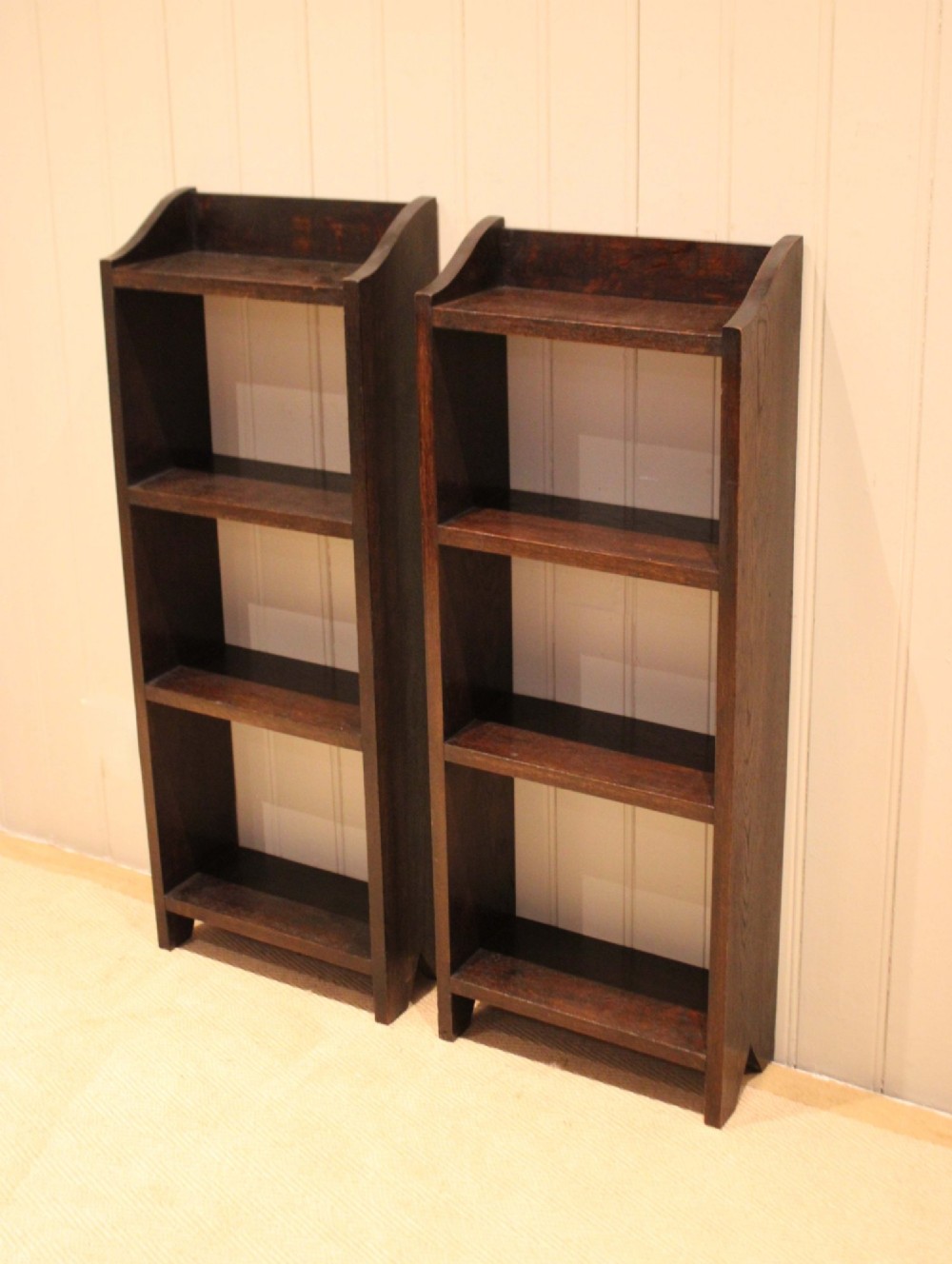 A small dark oak open bookcase featuring three open shelves filled with books and shaped side gallery panels at the top. View VIII