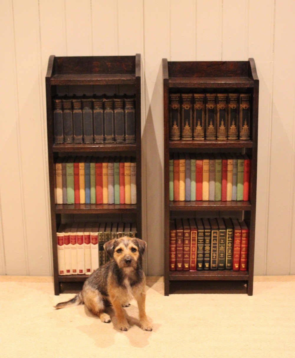 A small dark oak open bookcase featuring three open shelves filled with books and shaped side gallery panels at the top. View X