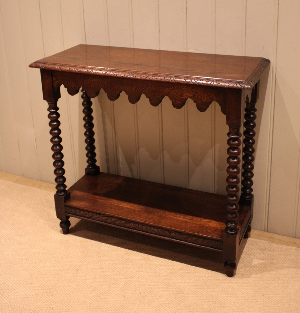 A dark oak console table featuring a rectangular top with carved moulding, a scalloped apron, four bobbin-turned legs, and a lower tier shelf. View II