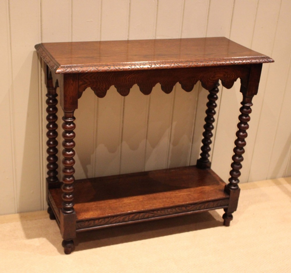 A dark oak console table featuring a rectangular top with carved moulding, a scalloped apron, four bobbin-turned legs, and a lower tier shelf. View III