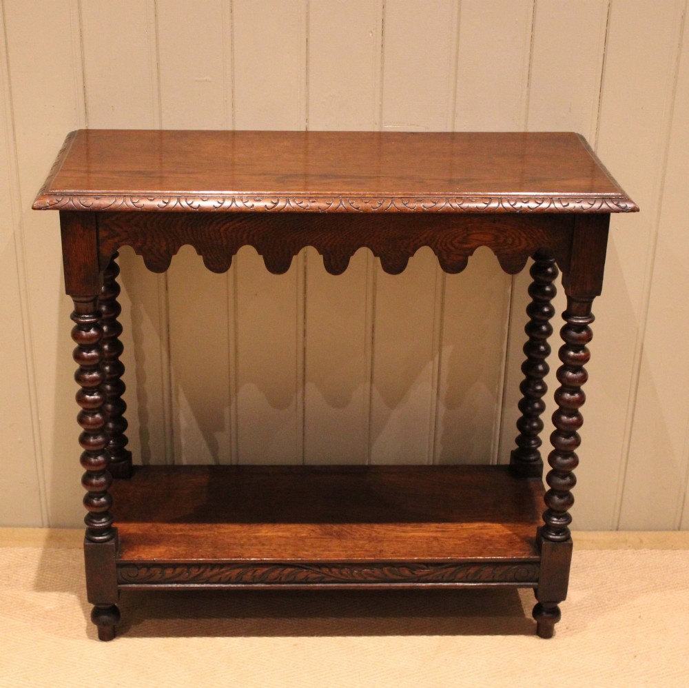 A dark oak console table featuring a rectangular top with carved moulding, a scalloped apron, four bobbin-turned legs, and a lower tier shelf. View IV