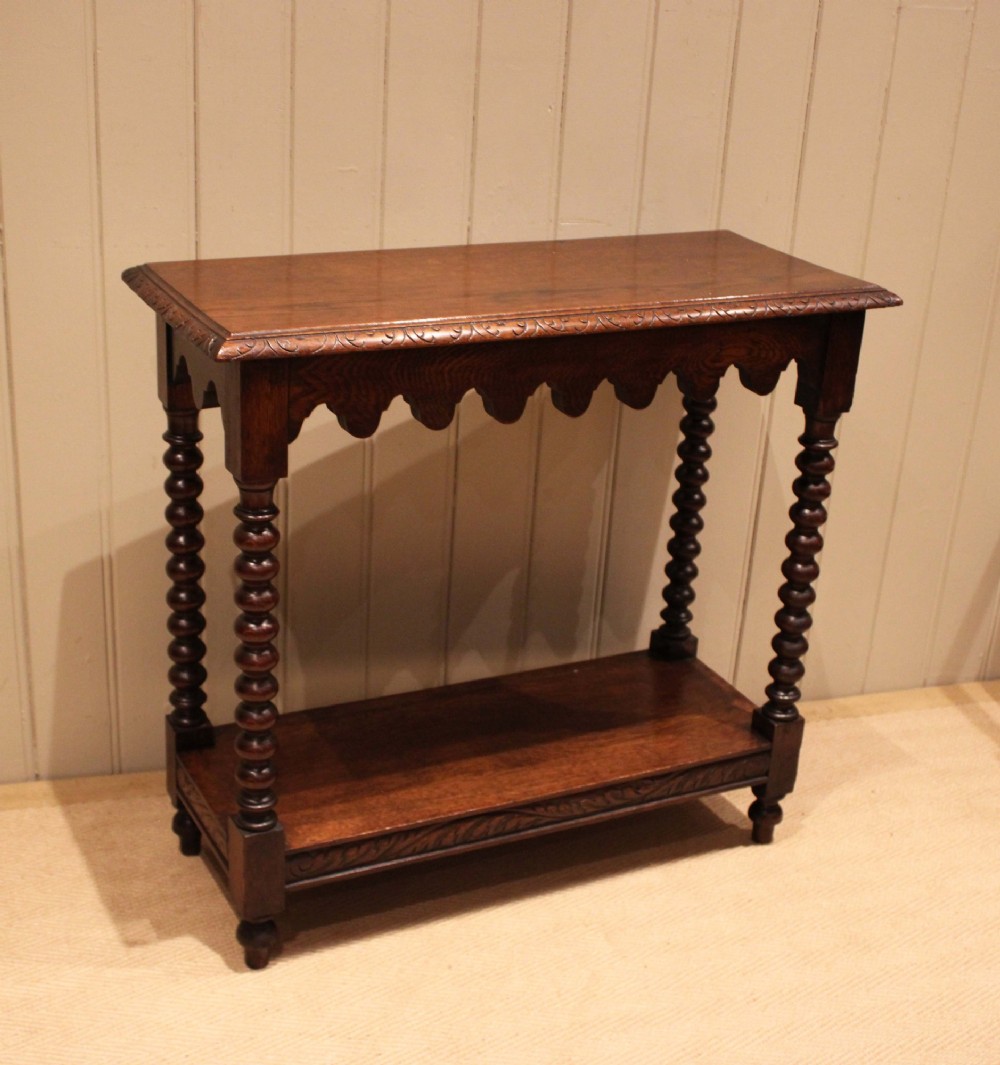 A dark oak console table featuring a rectangular top with carved moulding, a scalloped apron, four bobbin-turned legs, and a lower tier shelf. View VIII