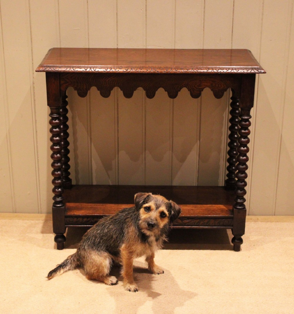 A dark oak console table featuring a rectangular top with carved moulding, a scalloped apron, four bobbin-turned legs, and a lower tier shelf. View IX