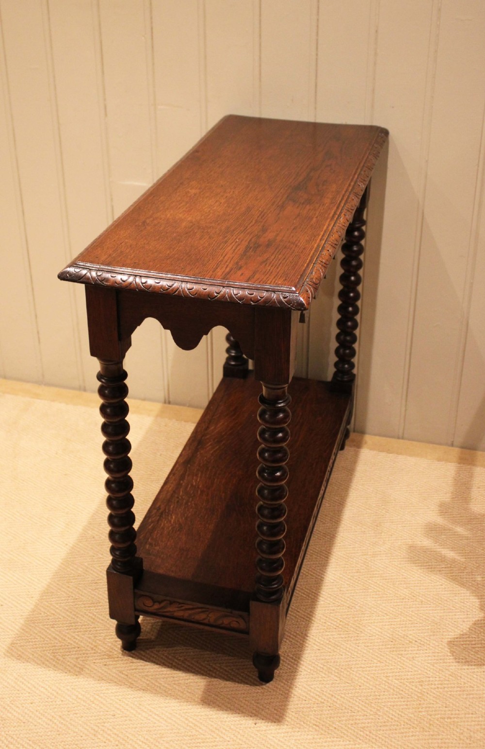 A dark oak console table featuring a rectangular top with carved moulding, a scalloped apron, four bobbin-turned legs, and a lower tier shelf. View XI