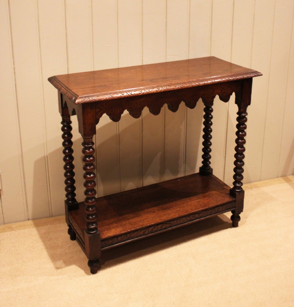 A dark oak console table featuring a rectangular top with carved moulding, a scalloped apron, four bobbin-turned legs, and a lower tier shelf. View XII