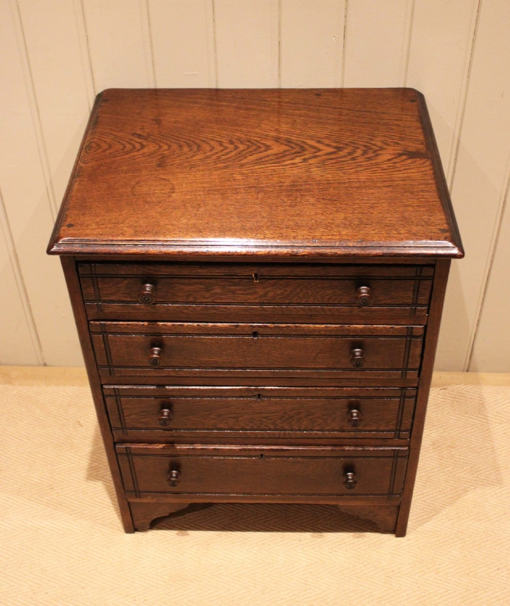 A small solid oak chest of four drawers featuring turned wooden knobs and incised border detailing. View II