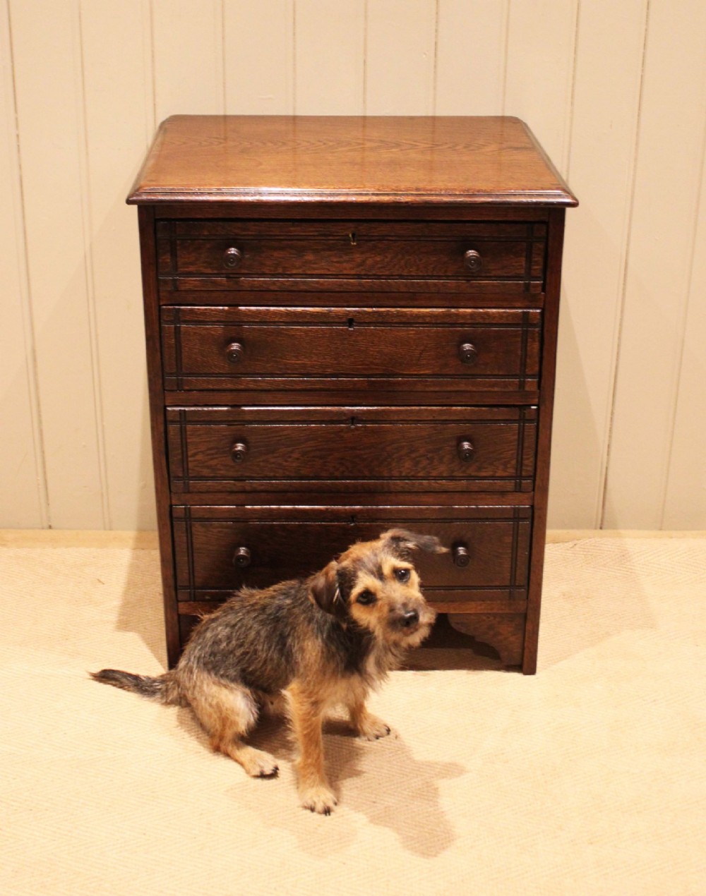 A small solid oak chest of four drawers featuring turned wooden knobs and incised border detailing. View VIII