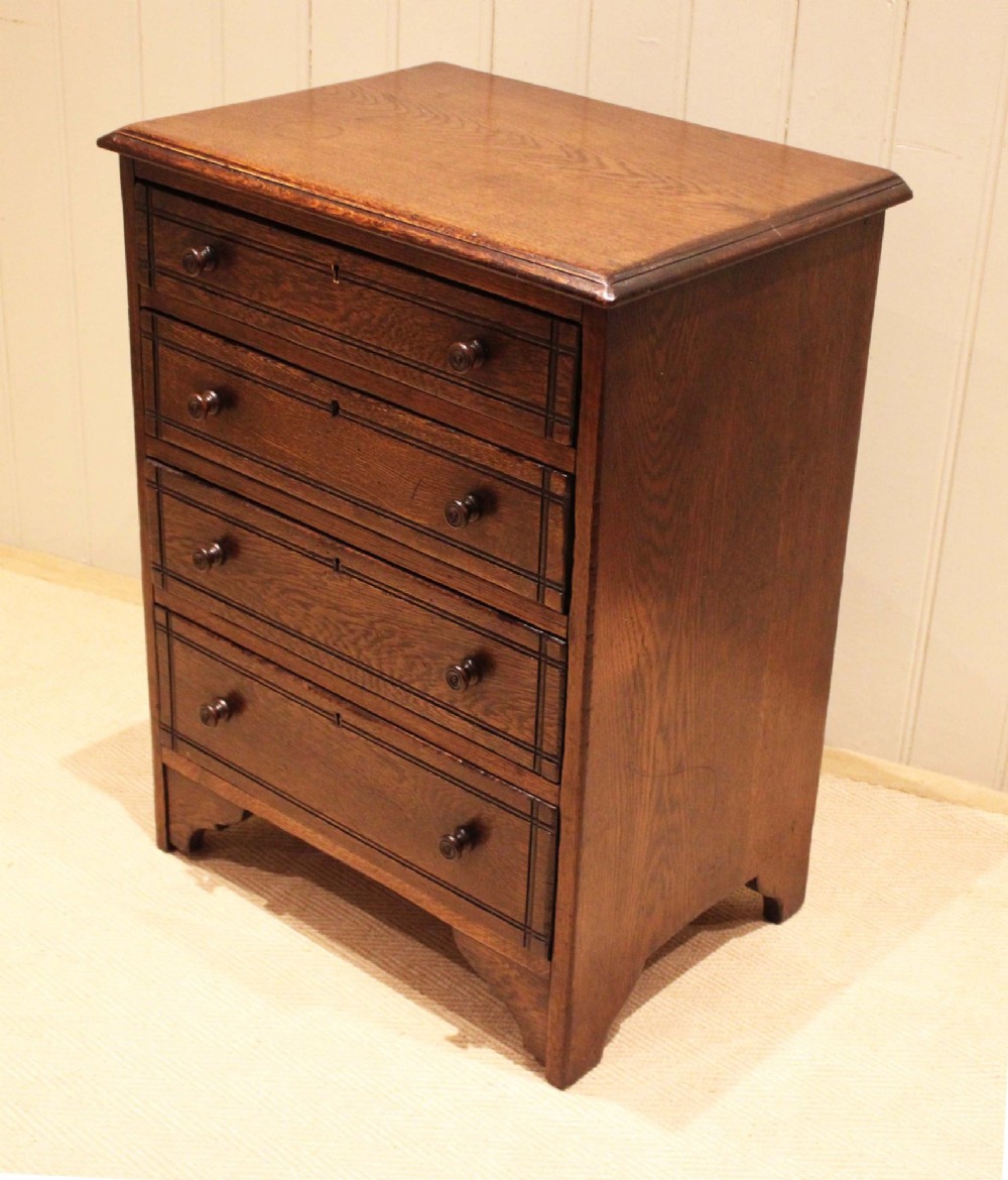 A small solid oak chest of four drawers featuring turned wooden knobs and incised border detailing. View XI