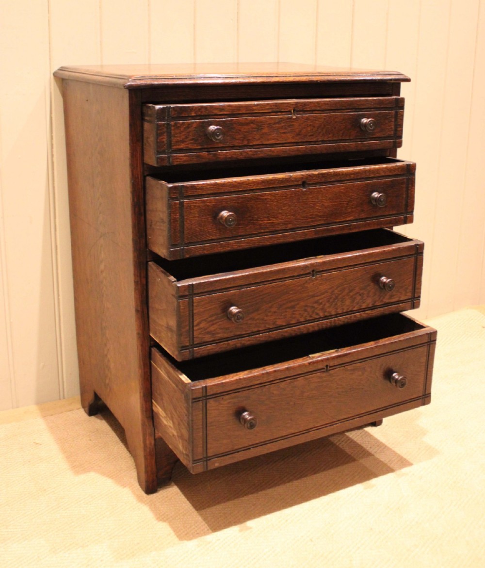 A small solid oak chest of four drawers featuring turned wooden knobs and incised border detailing. View XII
