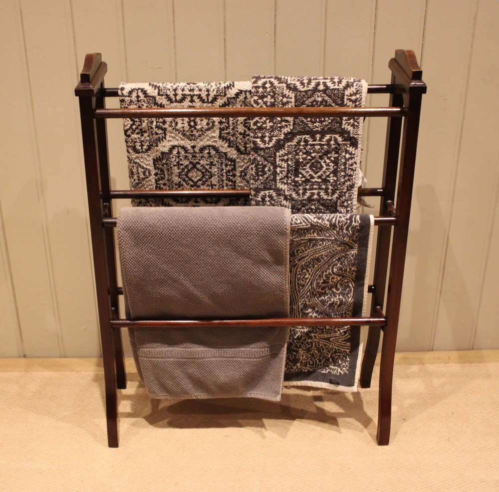 An Edwardian freestanding dark mahogany towel rail featuring six turned horizontal bars and splayed legs. View IV