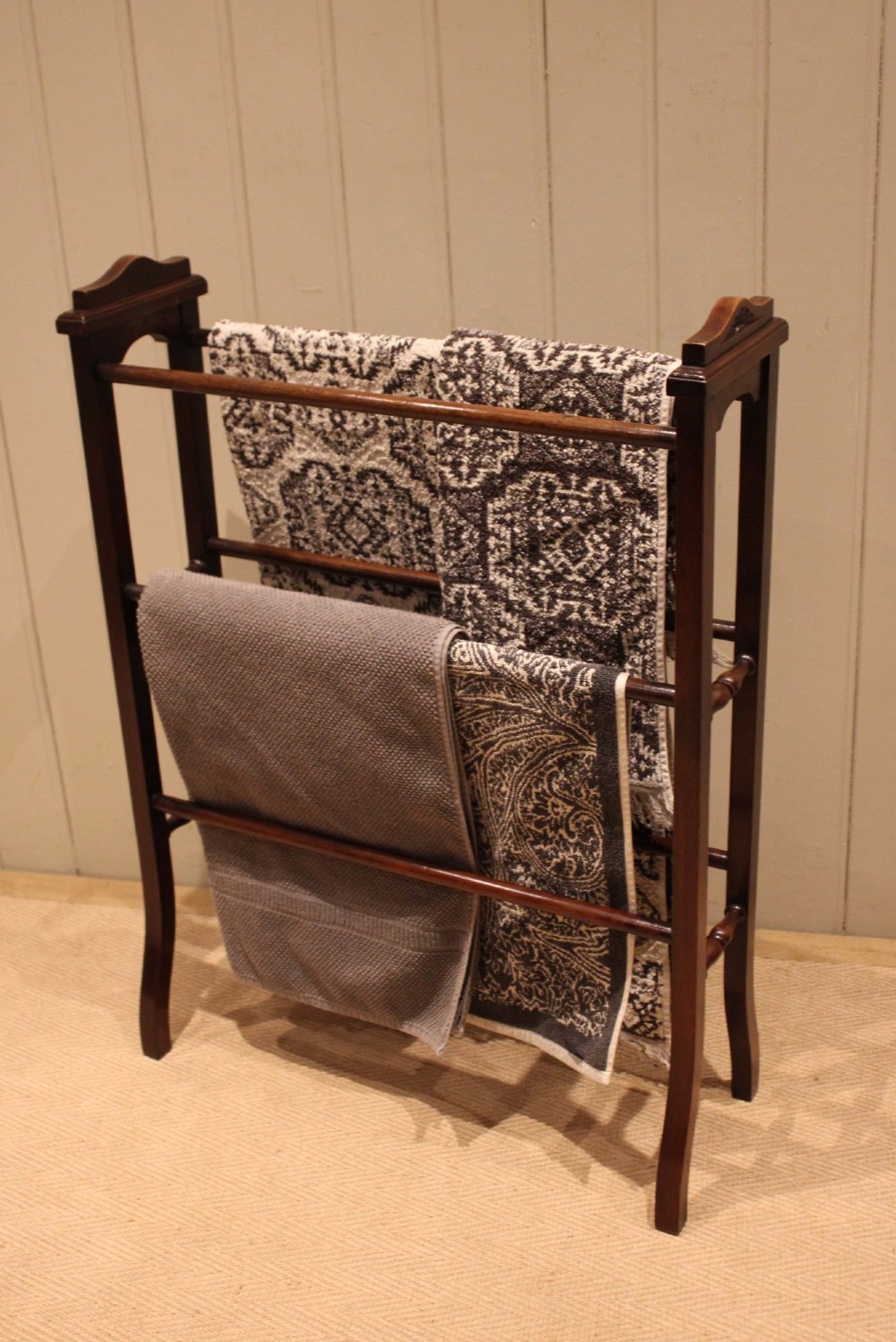 An Edwardian freestanding dark mahogany towel rail featuring six turned horizontal bars and splayed legs. View VI