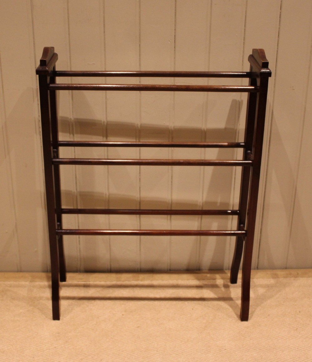 An Edwardian freestanding dark mahogany towel rail featuring six turned horizontal bars and splayed legs. View VII