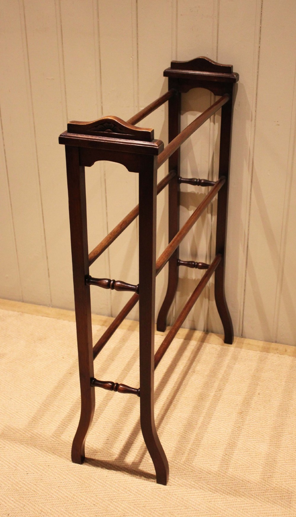 An Edwardian freestanding dark mahogany towel rail featuring six turned horizontal bars and splayed legs. View VIII