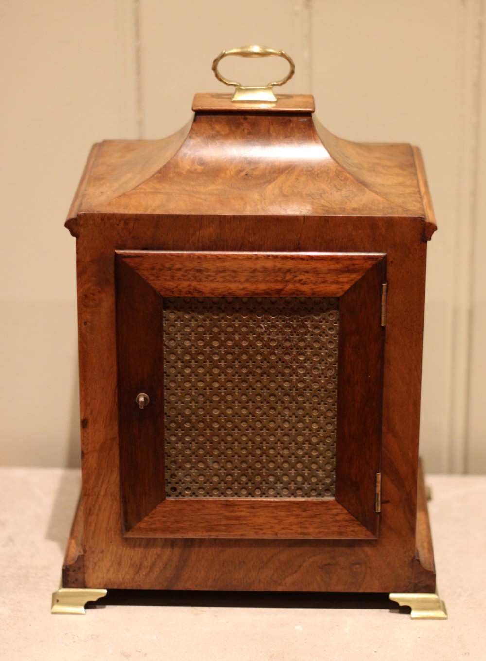 A burr walnut bracket clock featuring a caddy top with a brass carry handle, an ornate brass dial with a silvered chapter ring, and brass bracket feet. View VIII