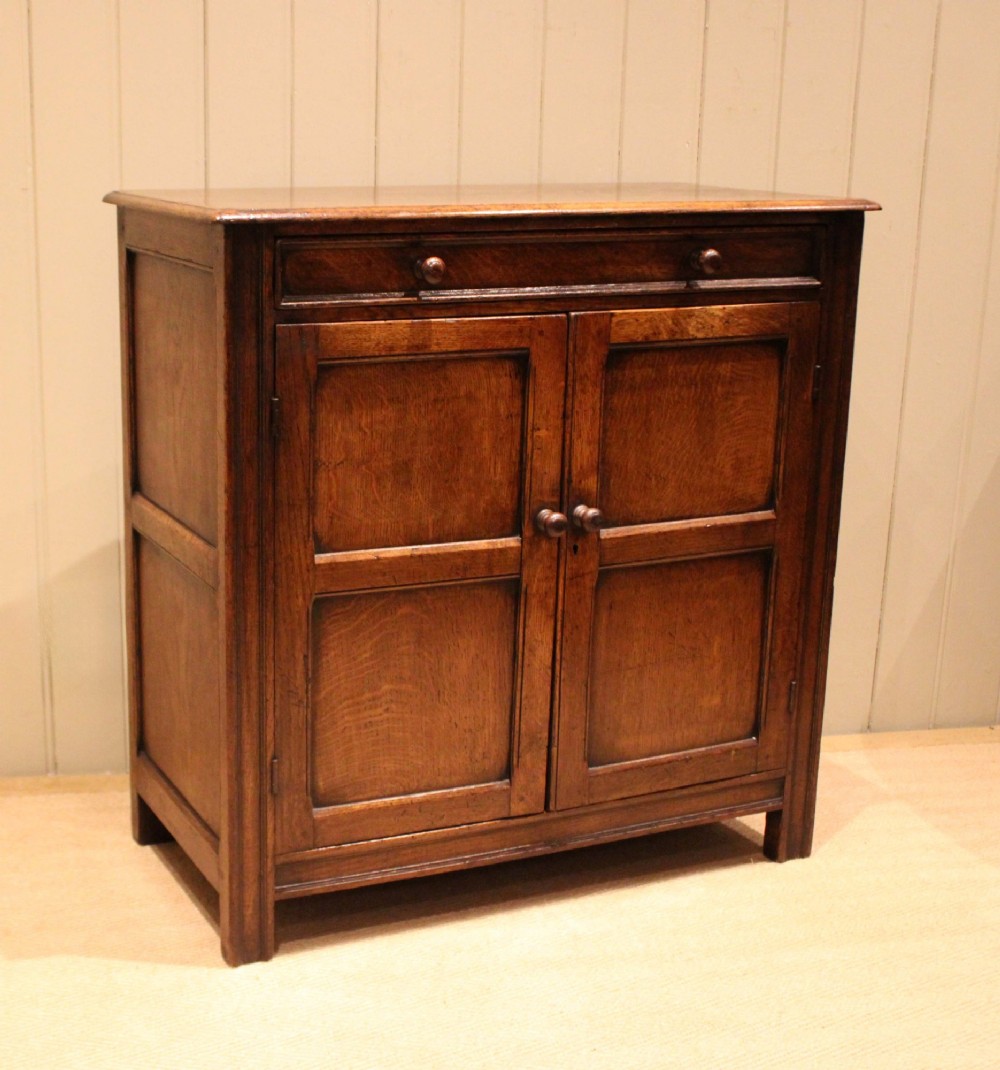 A late nineteenth-century solid oak side cabinet featuring a single top drawer above two panelled cupboard doors with turned timber handles. View II