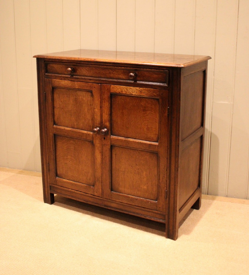 A late nineteenth-century solid oak side cabinet featuring a single top drawer above two panelled cupboard doors with turned timber handles. View V