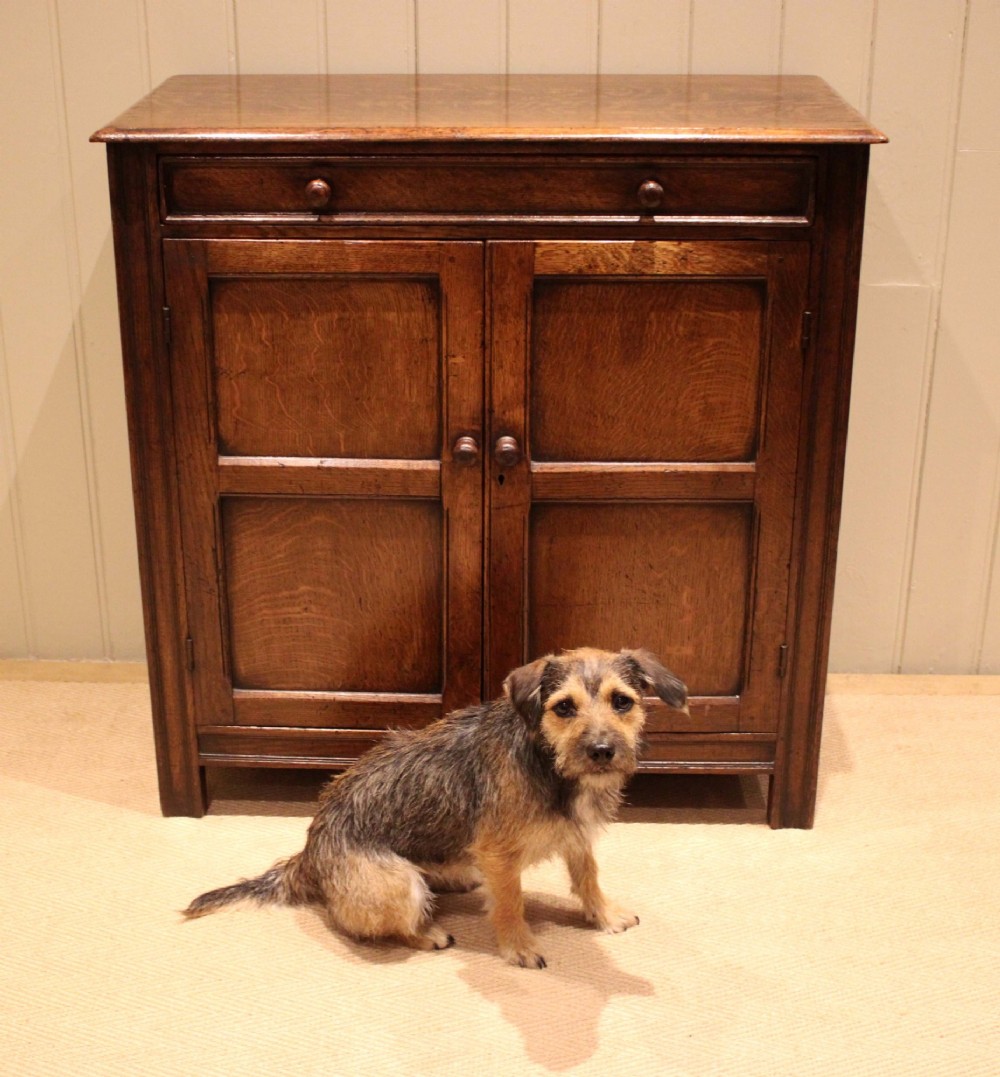 A late nineteenth-century solid oak side cabinet featuring a single top drawer above two panelled cupboard doors with turned timber handles. View VIII