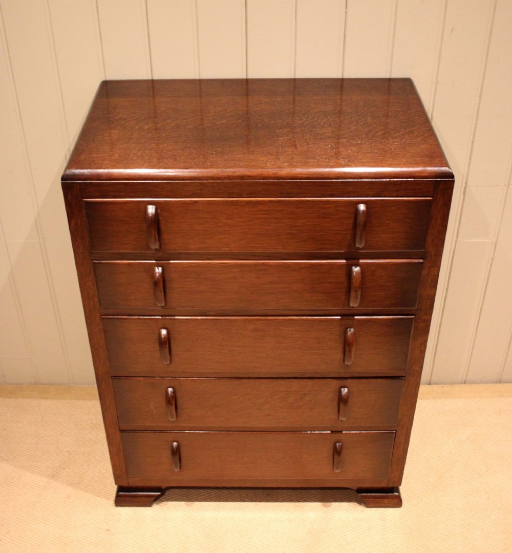 A dark brown oak Art Deco chest of drawers featuring five stacked drawers with matching wood handles and stepped feet. View IV