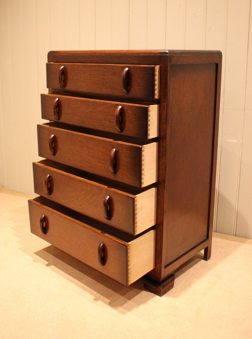 A dark brown oak Art Deco chest of drawers featuring five stacked drawers with matching wood handles and stepped feet. View VI