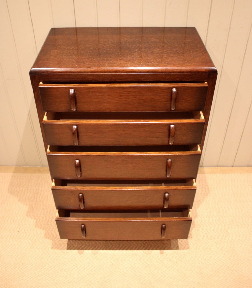 A dark brown oak Art Deco chest of drawers featuring five stacked drawers with matching wood handles and stepped feet. View VII